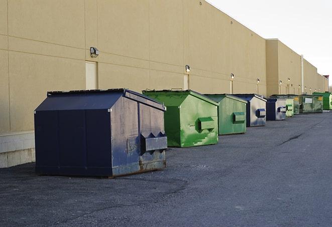 tilted front-load dumpsters being emptied by waste management workers in Fowler KS